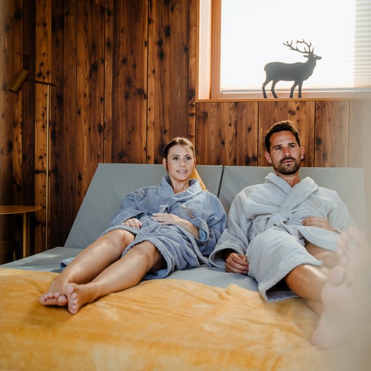 Young couple in bathrobe on cosy bed lounger