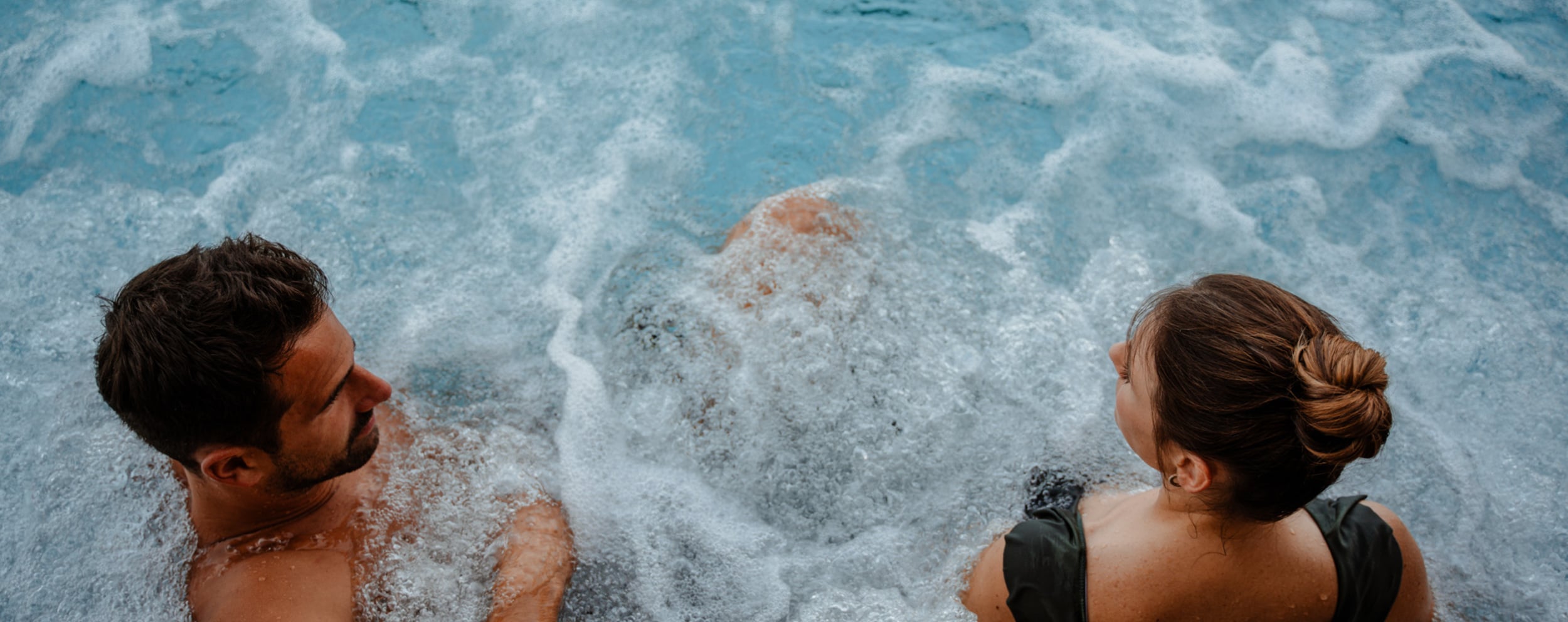 Mann & Frau sitzen bei Massagedüsen im Pool