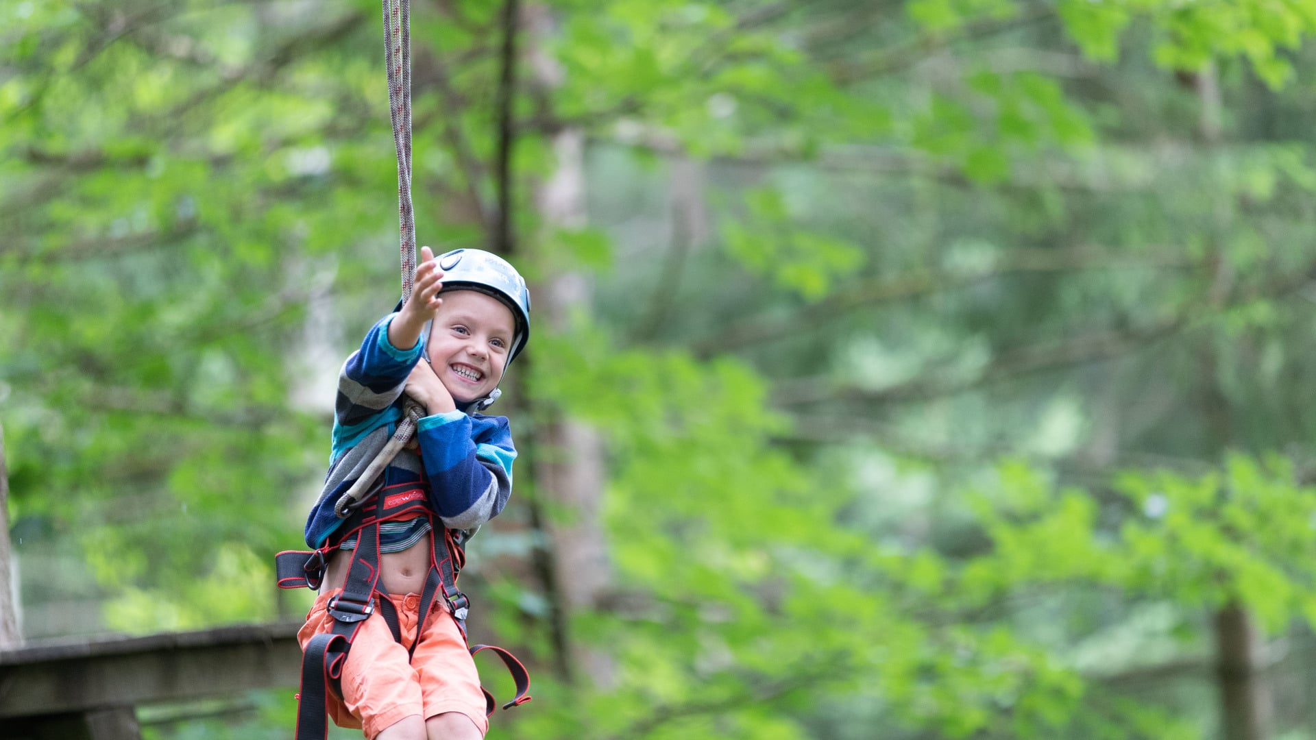 Kind auf Flying Fox im Wald im Klettergarten